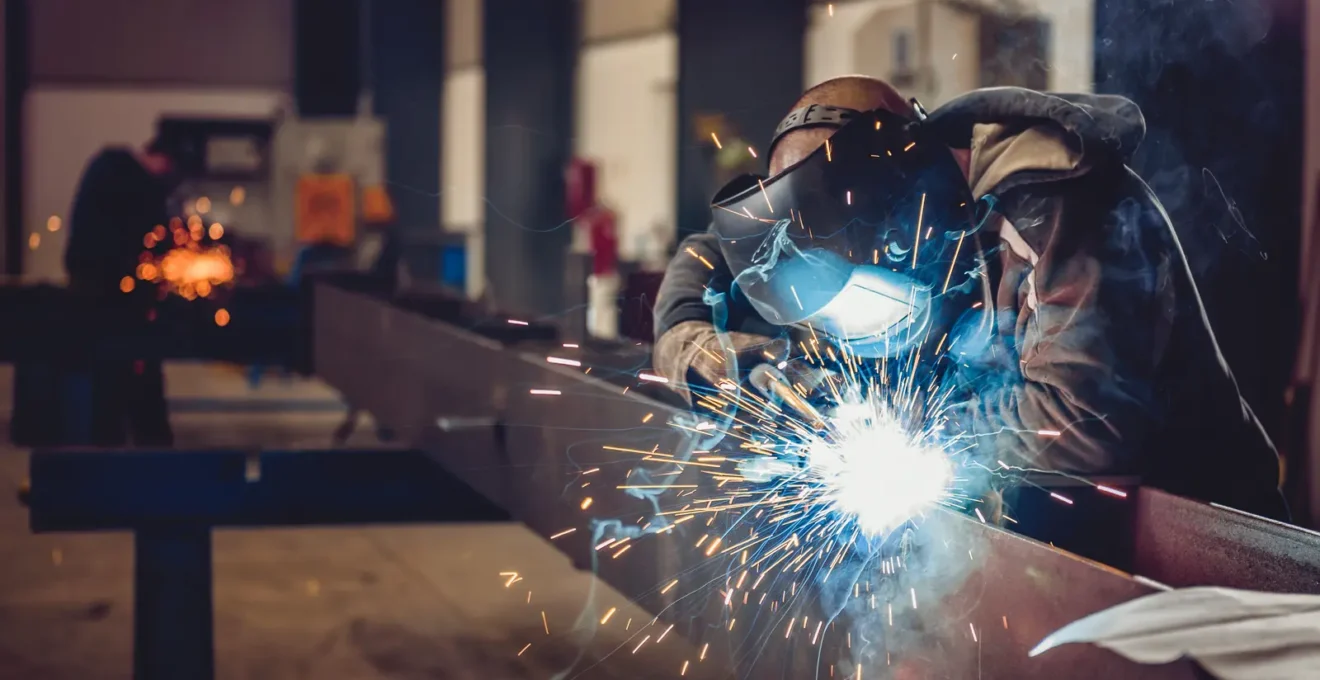 Soudeur réalisant une soudure sur des éléments de structure métallique préfabriqués en atelier